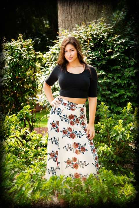 brunette teen girl in black with a white flower dress standing in the middle of bushes with her hand on her hip, mike moreland, creative edge photography workshops, intro to photography classes, atlanta photography courses, roswell photography club