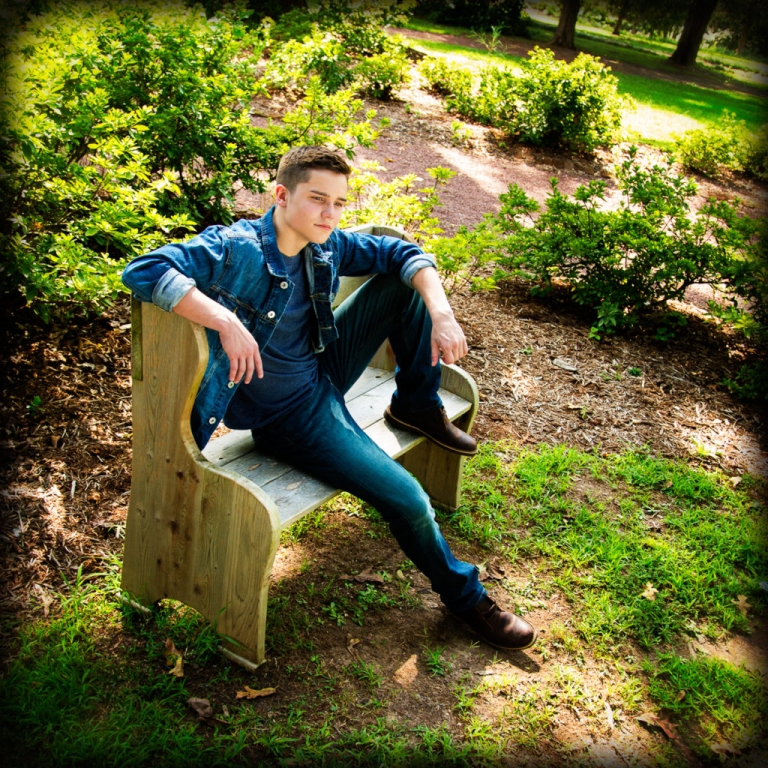teen boy in jeans and jean jacket sits leaning back on a bench in a garden, mike moreland, creative edge photography workshops, intro to photography classes, atlanta photography courses, roswell photography club